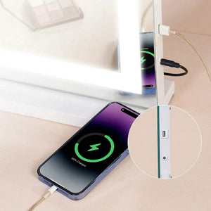 Detaliu al oglinzii Atelier în alb: telefonul încărcat din rama oglinzii, cercul cu portul USB și mufa DC